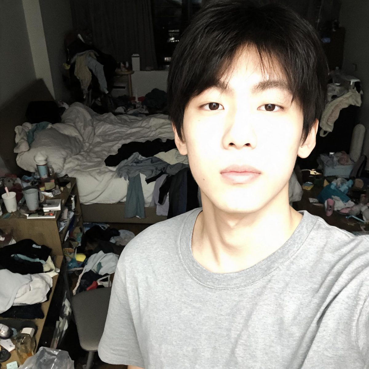 NG例：部屋が散らかった中での自撮り。フラッシュで顔が白飛びし、背景に荷物が散乱している